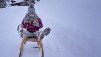 Kind rodelt den Berg runter